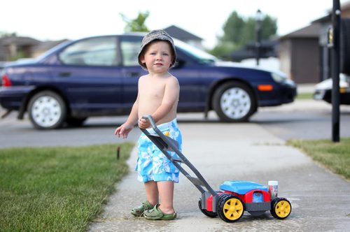 Brandon Sun 07072011 Nineteen-month-old Ashton Bickerton plays with a toy lawnmower on the sidewalk bordering Aurora Crescent in Brandon on Thursday afternoon. (Tim Smith/Brandon Sun)