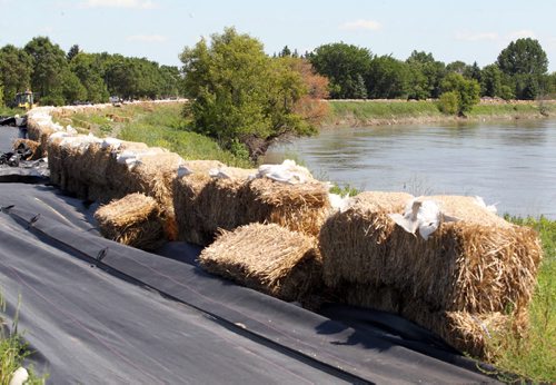 Brandon Sun Dikes, comprised of hay bales, sandbags and water-filled tubes known as "aqua dikes", line the riverbank along Kirkcaldy Avenue, Thursday afternoon. (Colin Corneau/Brandon Sun)