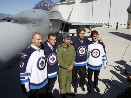 In centre, Col. Blaise Frawley with Winnipeg Jets players from left, Eric Fehr, Captain Andrew Ladd, Nik Antropov and Mark Stuart by a CF18 Hornet at a ceremony at 17 Wing Tuesday, where the Winnipeg Jets unveiled their dark home and white away jerseys.  see Tim Campbell story.  (WAYNE GLOWACKI/WINNIPEG FREE PRESS) Winnipeg Free Press Sept.6   2011