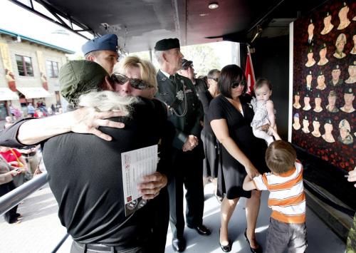 Shirley Seggie embraces artist Dave Sopha after viewing a portrait of her son on a newly unveiled travelling mural of 157 fallen Canadian soldiers, sailors and aircrew at the Forks Wednesday afternoon. Her daughter - Michelle,granddaughter Stella, grandson Carson and her husband jim (her rear) look on. The Kinsmen Club of Winnipeg has been selected as one of the stops on the Portraits of Honour Tour which was painted by artist Dave Sopha. Sept 28, 2011 Ruth Bonneville  Winnipeg Free Press