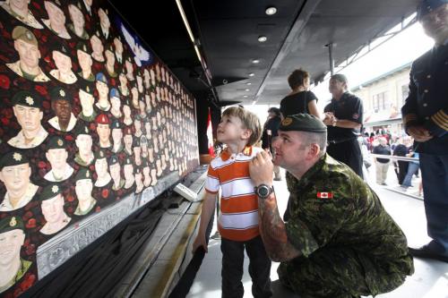 Three year old Carson Turner's dad (Matt) points to a painting of his uncle on a newly unveiled travelling mural of 157 fallen Canadian soldiers, sailors and aircrew at the Forks Wednesday afternoon.  The Kinsmen Club of Winnipeg has been selected as one of the stops on the Portraits of Honour Tour which was painted by artist Dave Sopha. Sept 28, 2011 Ruth Bonneville  Winnipeg Free Press