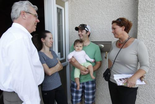 ELECTION - Premier Greg Selinger, left, and NDP's Theresa Oswald, right, do some door knocking in River Park South. Dana Collette, daughter Amelie (9 months), and Stephane Collette home.  .  Oct. 2, 2011 (BORIS MINKEVICH / WINNIPEG FREE PRESS)