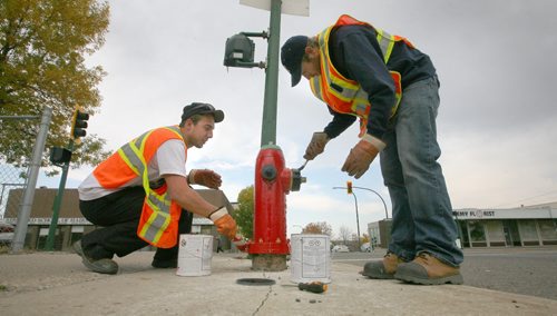 Brandon Sun City workers Stefan Woods and Eric Truscott, right, work to spruce up a downtown fire hydrant giving a new red and black look to the fixture at the corner of Sixth Street and Princess Avenue on Monday morning. (Bruce Bumstead/Brandon Sun)
