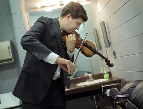Brandon Sun Violinist James Ehnes practices on his Stradivarius violin as he catches up on the Detroit Tigers baseball game on his smartphone, Tuesday evening at the Centennial Auditorium. The Brandon-born, world-renowned classical musician returned to his home town for an evening of chamber music with pianist Andrew Armstrong. (Colin Corneau/Brandon Sun)