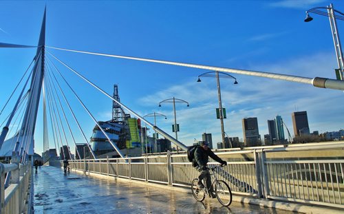 A bicyclist rides over the Esplanade Riel with the partially finished Canadian Museum for Human Rights and downtown Winnipeg in the distance Thursday afternoon.  111124 Mike Deal / Winnipeg Free Press
my2011poy CMHR