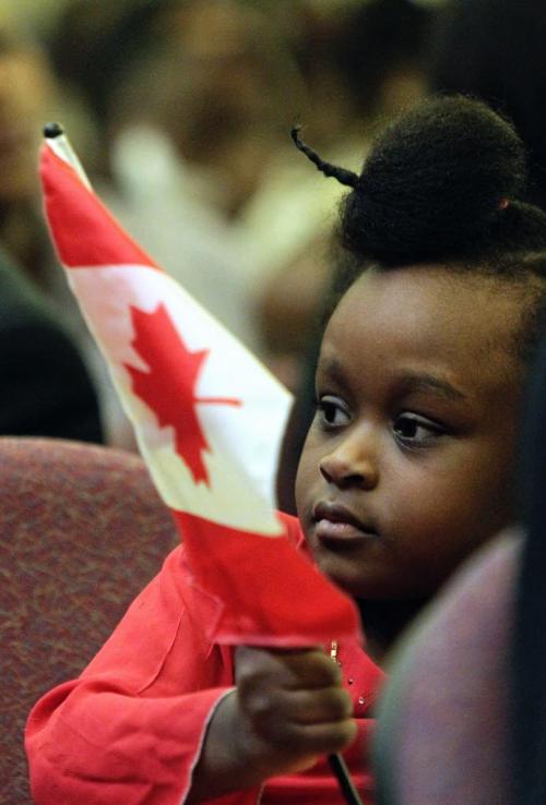 Divine Mugugu, 4, waves a flag after reaffirming the oath of citizenship at the Union Station Citizenship Court on Friday. Divine was born in Canada, but her mother, father and other members of her family became citizens at today's ceremony.   111125 Mike Deal / Winnipeg Free Press