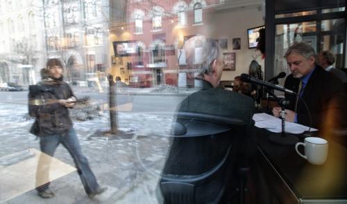A pedestrian is reflected in the window as he walks by the Winnipeg Free Press News Café while John Harris president and CEO of Prairie Public Broadcasting (right) interviews Colin Ferguson president of Travel Manitoba for a live segment on PBS radio at the Café. Some of his other guests were Free Press City Editor Paul Samyn and Mayor Sam Katz. 111209 Mike Deal / Winnipeg Free Press