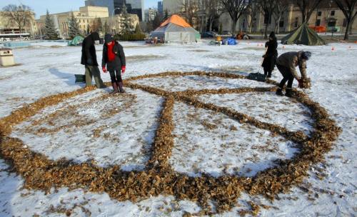 Occupy Winnipeg update. After cleaning out camp a small group of tents and occupiers hold tight on the grounds across from the Manitoba Legislature Building.  Some occupiers make a peace sign with some leaves left over. December 11, 2011 BORIS MINKEVICH / WINNIPEG FREE PRESS