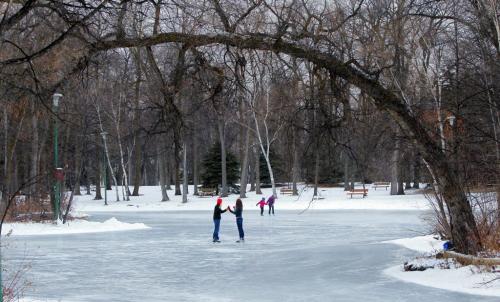 Some lovers embrace on St. Vital Park pond under the scenic background of a arched trees and sparkling snow. The pond at the park was perfectly smooth and must have been flooded in the last day or so.  December 22, 2011 BORIS MINKEVICH / WINNIPEG FREE PRESS