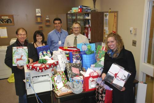 Brian McMillan (left) and Caitlin MacGregor (right) of Home Instead Senior Care with staff from the University of Manitoba surrounded by gifts students from the Faculty of Dentistry collected. Photo copyright Home Instead Senior Care  - for Nick Ashdown story / winnipeg free press