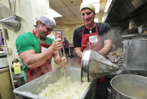 DJ Guzda (left) and Garth Cuddy (right) volunteer at the mashed potato station in the kitchen at Siloam Mission during the annual Christmas dinner. 111224 Mike Deal / Winnipeg Free Press