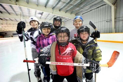 A group of elementary kids smile as they stop for a quick photo while shooting pucks around the ice and learning to skate at Ebb and Flow arena after school.  The community is exploding with children in the last 5 years. The the K to 12 school built in the 80's for 200 students is now bursting at the seams with over 700 students.   Names of students from centre to left - Chase Houle (Red Canada shirt), Joclynn Houle (girl in purple), Matthew McIvor (white helmet), Layne Houle (black helmet, back centre), Rueben Houle (blue helmet) and Leland Malcoln (green).  See Mary Agnes Welch story on Ebb and Flow First Nation. Jan 25, 2012 (Ruth Bonneville /  Winnipeg Free Press)