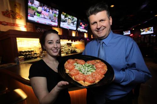Holding a special vegetarian heart shaped pizza, Caitlyn Fecyk (left), a server at Boston Pizza on Portage Avenue, and Andrew Shefchyk, director of marketing for Boston Pizza-Enright Group, which owns and operates 11 Boston Pizza restaurants in Manitoba. See Murray McNeill story  120201 Mike Deal / Winnipeg Free Press