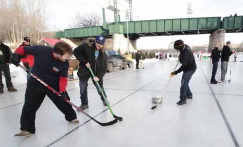 (l-r) John Ferguson, Spencer Mackie and Willie Mackie sweep with hockey sticks as members of Team Rock Hard during the 11th annual Ironman Outdoor Curling Bonspielon the Assiniboine River at The Forks on Friday. The event runs until Sunday. 120204 Mike Deal / Winnipeg Free Press