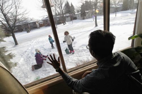 Melvin Durai who wrote a response to a Bartley Kives column on embracing winter waves to his kids (l-r) Divya, 8, Rahul, 5, and Lekha, 9. He doesn't like winter (he is from Kenya) but his kids love it. 120225 Mike Deal / Winnipeg Free Press