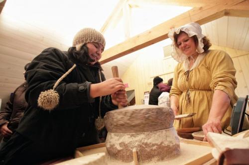 Chantal Theriault (right) from the Manitoba Living History Society shows Wawatay Beardy (left), 12, how to use a traditional quern used for making flour from wheat grains while at a display in Fort Gibraltar at the Festival du Voyageur Saturday. 120225 Mike Deal / Winnipeg Free Press