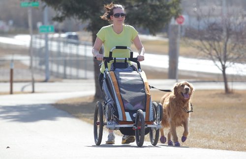 Brandon Sun Tilda Fortier takes advantage of the spring-like weather in walking with her dog and child along the 34th Street walking paths on Friday. FOR STREETER (Bruce Bumstead/Brandon Sun)
