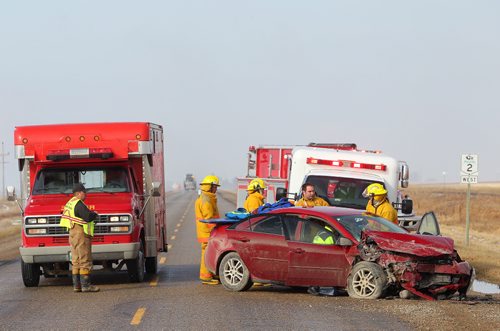 Brandon Sun 28032012 Firefighters and paramedics work to extricate the driver of a car involved in a two-vehicle collision with a pickup truck on Highway 2 east of Souris on Monday morning. The driver of the car was taken to hospital by ambulance. Both eastbound and westbound traffic was backed up along the highway while emergency crews worked at the scene.   (Tim Smith/Brandon Sun)