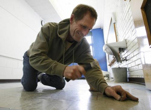 John Woods / Winnipeg Free Press / February  2 2007 - 070202  - On Friday, Feb., 2/07 Kirk McMillan, a carpenter with the Winnipeg School division, nails down floor tiles at Sir Sam Steele School on Nairn in preparation for students who can not attend their school because of flooding.
