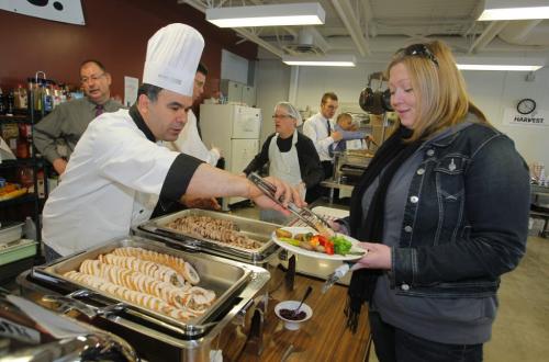 Ali Chioua, Lakeview corporate chef, serves up some grub to Amanda Wiebe, a volunteer's aid, at the turkey lunch at Winnipeg Harvest. Four Points by Sheraton has donated 30 turkeys to Winnipeg Harvest to help with its desperate need for food items. Four Points by Sheraton will turn over the high protein birds this morning at the food bank before a cooking demonstration. The donation is in response to the urgent food crisis facing Harvest and comes just in time for the holiday weekend. Despite the large donation, more non-perishable food items are still needed and can be dropped off at any Canada Safeway location or the food bank in-person at 1085 Winnipeg Avenue. (info from the internet) April 3, 2012  BORIS MINKEVICH / WINNIPEG FREE PRESS