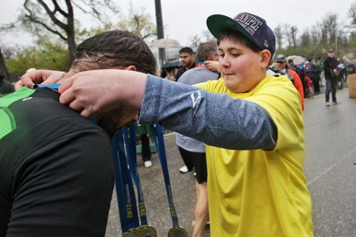 Ryan Veldkamp, 15, hands out medals to participants after they cross the finish line.  Around 1,900 people took part in the Winnipeg Police Service half-marathon this morning. The eighth annual event started and finished at Assiniboine Park and is expected to raise about $100,000 for Cops for Cancer. Organizers had initially expected about 2,500 participants, but said the weather may have dissuaded some people from coming out. See Jen Skerritt story 120506 May 06, 2012 Mike Deal / Winnipeg Free Press