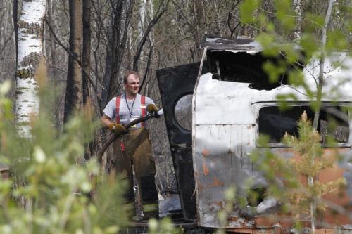 A firefighter works to extinguish the remains of a trailer destroyed be forest fires near Vita, in southeastern Manitoba, on Monday. May 14, 2012. SARAH O. SWENSON / WINNIPEG FREE PRESS