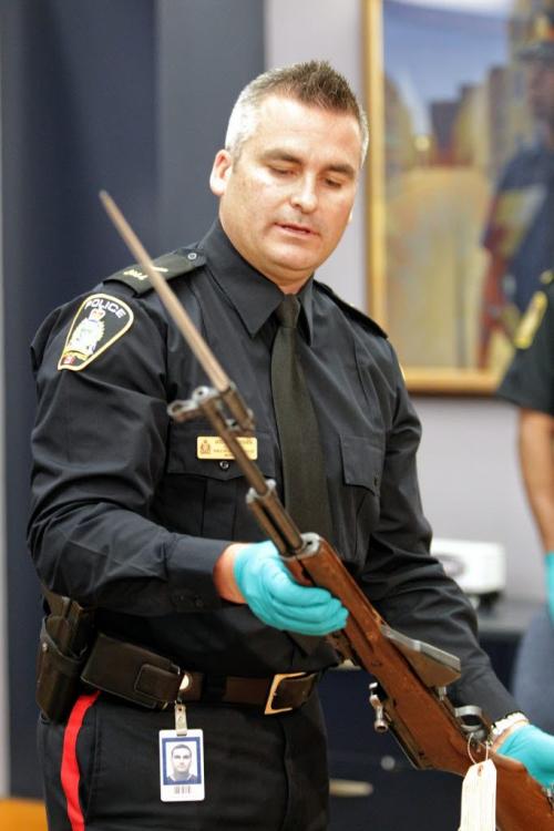 Public Information Officer Jason Michalyshen handles one of guns seized during a drug bust in the 100 block of Vivian Ave. last night at a press conference at the Public Saftey Building. 120513 May 13, 2012 Mike Deal / Winnipeg Free Press
