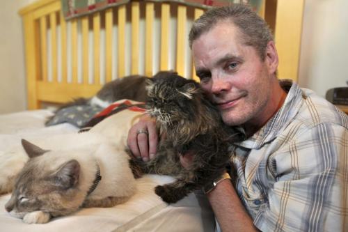 Darcy Canty with his 3 cats - scraggly persian cate "Kiki" and his two other's at his home. 
Names of cats - "Kiki" dark Persian, "Jinxy" cream and "Sylvestor" black and white.
 See Gordon Sinclair story Photo Ruth Bonneville Winnipeg Free Press