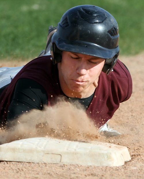 Brandon Sun Crocus Plains' Kyle Johnston sprays up a cloud of dirt as he dives back to first base to avoid a pickoff attempt by the Vincent Massey pitcher, Wednesday evening at Andrews Field. (Colin Corneau/Brandon Sun)