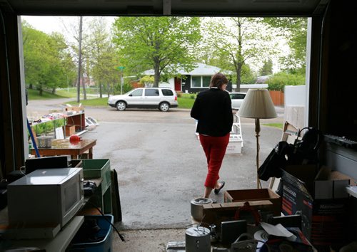 Brandon Sun A woman walks out of a garage into a spring rain while shopping at a yard sale on Second Street North, Friday afternoon. (Colin Corneau/Brandon Sun)