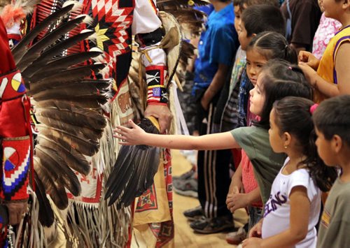 Brandon Sun A young student reaches out to touch the eagle feathers on a dancer's clothing during the 7th annual Spring Powwow, Friday afternoon at New Era School. The event featured a sunrise ceremony, drummers, dancers, a feast and other expressions of aboriginal culture. (Colin Corneau/Brandon Sun)