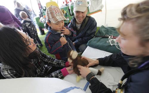 May 27, 2012 - 120527  - Jordan Li, with mom and dad, David and Xiao-Huan watches as Winnipeg Paramedic Nikki Little puts a bandage on his monkey at the 26th annual Teddy Bear's Picnic at Assiniboine Park Sunday May 27, 2012 .  John Woods / Winnipeg Free Press