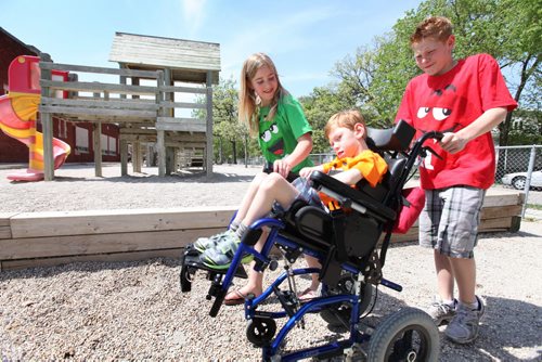Griffin and his sister Emily push their brother Tyler along the gravel next to their schools play structure during the lunch hour.  Griffi'n's grade 7 class is raising money for a new structure that will allow Tyler who has cerebral palsey to use it.  See ongoing series on the class of 2017( at Windsor School. See Doug Speirs story Windsor School 2017 project. May 28  2012 (Ruth Bonneville/Winnipeg Free Press)
