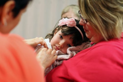 Brandon Sun 18062012 Public Health Nurse Tammy Fisher puts a band-aid on five-year-old Bailee Romeril as she is held by her mother Robyn after getting her immunizations during a Pre-Kindergarten Immunization Clinic at the Brandon RHA - Public Health Unit in the Town Centre on Monday. (Tim Smith/Brandon Sun)