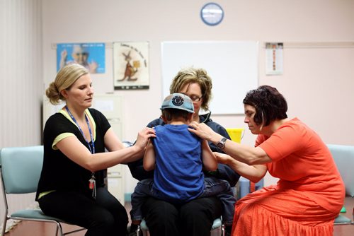 Brandon Sun 18062012 Public Health Nurses Wendy Brock and Tammy Fisher prepare Konner McKay for his immunizations as he is held by his mother Carrie during a Pre-Kindergarten Immunization Clinic at the Brandon RHA - Public Health Unit in the Town Centre on Monday. (Tim Smith/Brandon Sun)