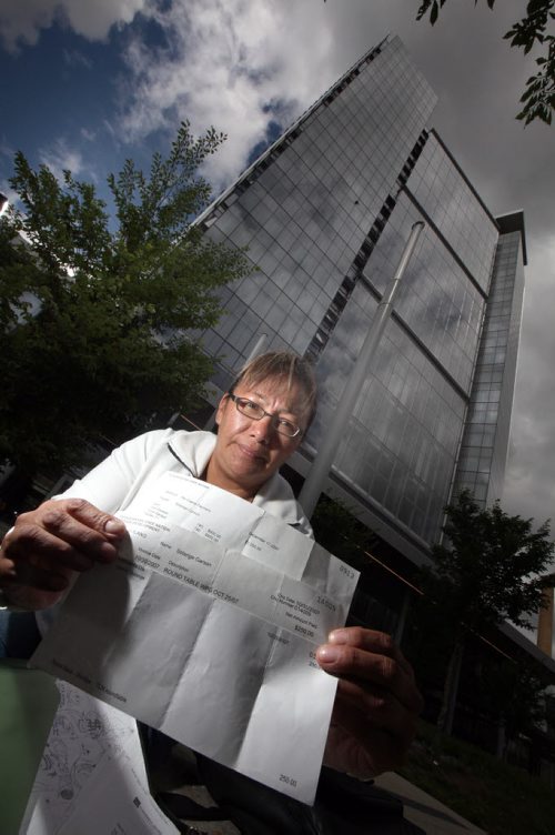 Posing in front of the Mb Hydro Building in Winnipeg, Solange Garson of the Tataskweyak Cree Nation brandishes cheque stubbs she says Hydro Officials and/or their representatives paid her and other community members to attend meetings about development in their community. See Layy Kush story. June 20, 2012 - (Phil Hossack / Winnipeg Free Press)