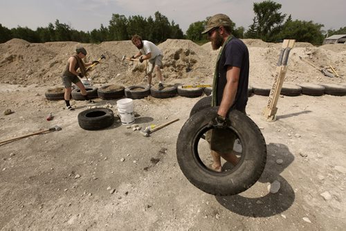 July 2, 2012 - 120702  - Kris Plantz (R) moves tires into position while his friend Bill Zenert and his wife Nicole Bennett pound dirt into tires at their building site Monday, July 2, 2012. Bennett and Plantz are building the provinces first earthship  an eco-friendly home built with dirt-filled tires and bottle bricks.   John Woods / Winnipeg Free Press  This is for feature on Manitobans living off the grid. Re: Carolin Vesely