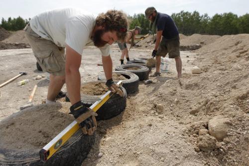 July 2, 2012 - 120702  - Bill Zenert  checks the level of some dirt filled tires while Kris Plantz (R) and his wife Nicole Bennett  (C) pound dirt into tires at their building site Monday, July 2, 2012. Bennett and Plantz are building the provinces first earthship  an eco-friendly home built with dirt-filled tires and bottle bricks.   John Woods / Winnipeg Free Press  This is for feature on Manitobans living off the grid. Re: Carolin Vesely