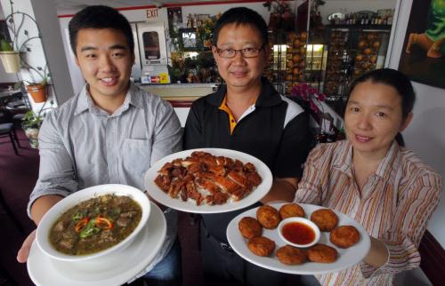RESTAURANT REVIEW - Thai Bochi. Family business-Charles Ung, Chhay Ung, and Kanyarat Ung pose for a photo with Sour Beef Soup, Marinated Grilled Chicken, and Thai Fish Cakes. 870 Logan Ave. July 11, 2012  BORIS MINKEVICH / WINNIPEG FREE PRESS