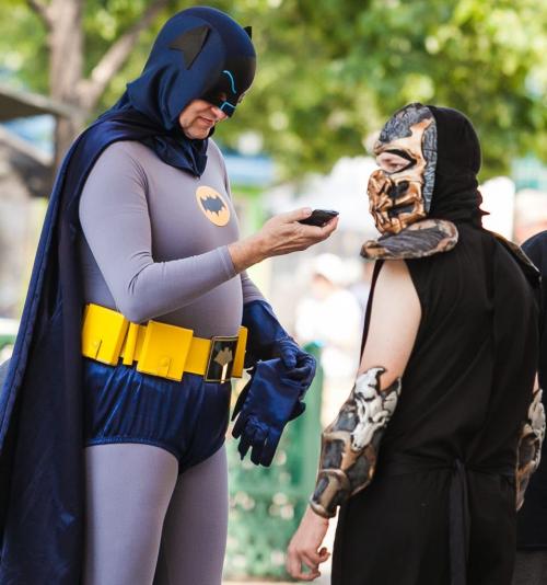 Classic Batman - or Greg Young of Winnipeg - checks his cell phone while offering photo opportunities to visitors at The Forks on Saturday afternoon. Young, a big fan of Adam West, made the costume himself over three years. Alongside Batman is Scorpion, from the Mortal Kombat video game. 120714 - Saturday, July 14, 2012 -  Melissa Tait / Winnipeg Free Press