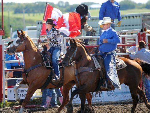 Brandon Sun Lacey Marshall carries the Canadian flag alongside her father Terry, Saturday afternoon during the grand entry of the Minnedosa Rodeo. The event runs through Monday. (Colin Corneau/Brandon Sun)