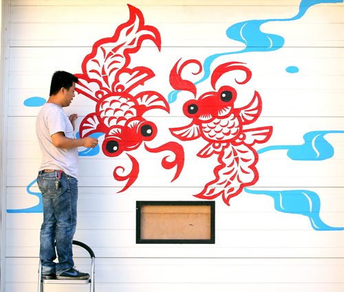 Brandon Sun Weidong Cong touches up a mural painted onto the door of his grocery store, Sunday afternoon on Rosser Avenue near Twelfth Street. Cong has opened the North China Supermarket, and commissioned a painting along the door as well as a side wall of his new business. (Colin Corneau/Brandon Sun)
