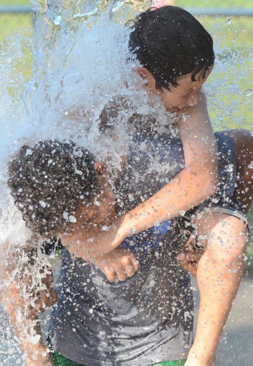 201208229 Winnipeg -  Brothers Isaiah Jackson, age 11, gives his brother Vincent Cornejo, age 12 a piggyback ride as they stand under the tipping bucket of water at the Vimy Ridge Park splash pad in Woleseley.  August 29 2012 (COLE BREILAND / WINNIPEG FREE PRESS)