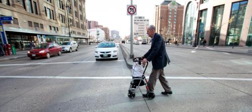 Eighty seven year old John Clark makes his way across Portage Ave. at Vaughan St. with his walker and small bag of groceries that he purchased at the grocery store in the basement at The Bay downtown.  Since he doesn't drive he is worried about where he will be able to buy his groceries once the grocery store closes. See Carol Sanders story. Oct 16,  2012 (Ruth Bonneville/Winnipeg Free Press)