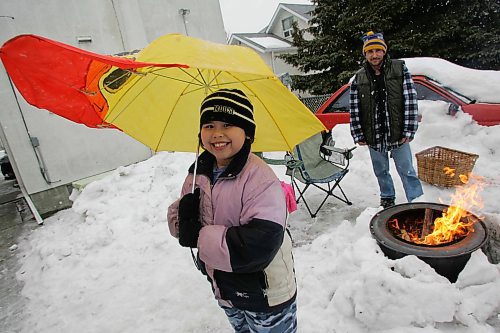 BORIS MINKEVICH / WINNIPEG FREE PRESS  070318 Nadia Fedon,8, holds her summer sunbrella in hopes of spring in her backyard with her dad Richard. They were sick and tired of the winter and started their first backyard fire of the year. WEATHER STANDUP.
