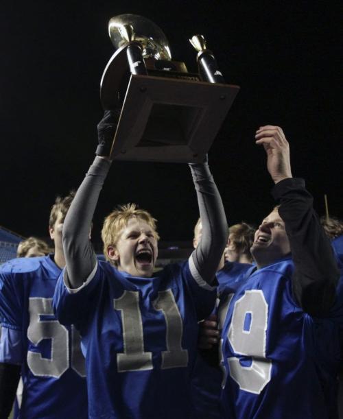 Oak Park Raiders Riley Dirks (11) hoists the trophy after the team won the championship game 30-15. The Oak Park Raiders and Vincent Massey Trojans played in the Home Run Sports Bowl at Canad Inns Stadium Thursday evening. The Raiders won the game 30-15. 121108 - Thursday, November 08, 2012 -  (MIKE DEAL / WINNIPEG FREE PRESS)