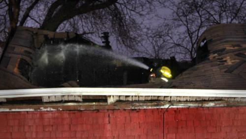 Winnipeg Fire Fighter hoses down hot spots in the roof at the scene of a house fire on Hethrington Ave. Thursday morning. (WAYNE GLOWACKI/WINNIPEG FREE PRESS) Winnipeg Free Press  Nov. 22   2012