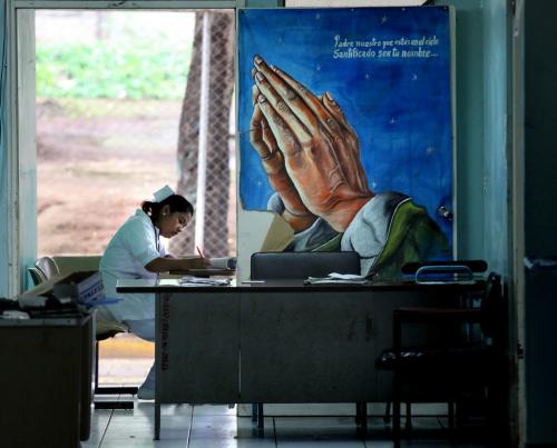 Wearing a traditional nurses "cap" a nicaraguan nurse takes care of record keeping behind a prayer poster on an emergency ward in Managua.  Phil Hossack / Winnipeg Free Press October 25, 2012