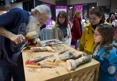 121124 Winnipeg - Brock Blosser of 'Wood With Whimsey' works on a piece as (L-R) Erna Moir, and Irina and Mishel (age 10) look on Saturday afternoon at the Signatures Craft Show & Sale. DAVID LIPNOWSKI / WINNIPEG FREE PRESS