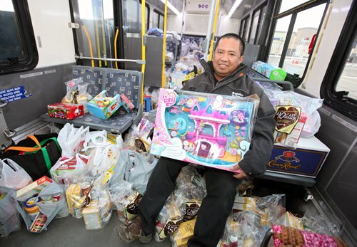 Brandon Sun 24112012 Brandon Transit Driver Nur Hidayat sits with all the food and toys that were donated during the 2012 "Fill the Bus" campaign in the Corral Centre Safeway parking lot on Saturday. Donations from the three-day campaign will go to support the Christmas Cheer Registry. (Tim Smith/Brandon Sun)